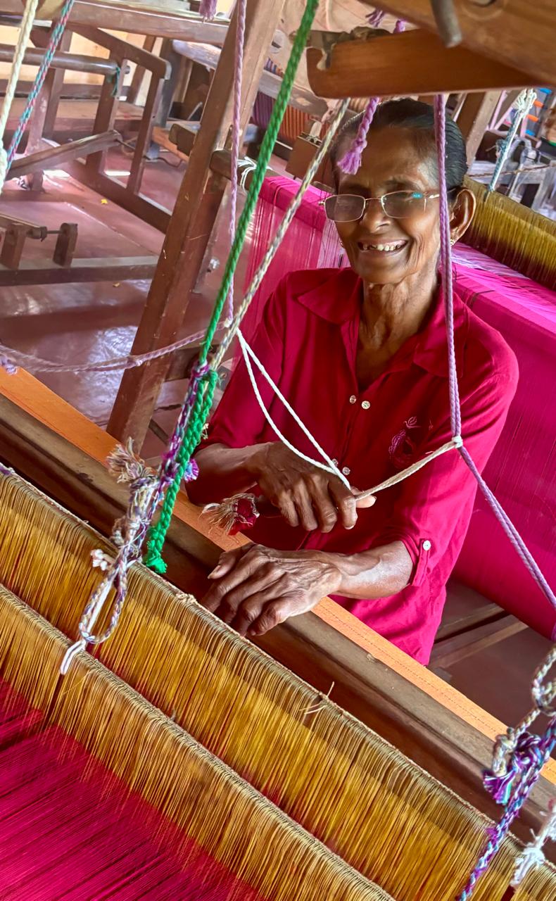 A local weaver smiling while working a traditional hand loom at Hambu Café